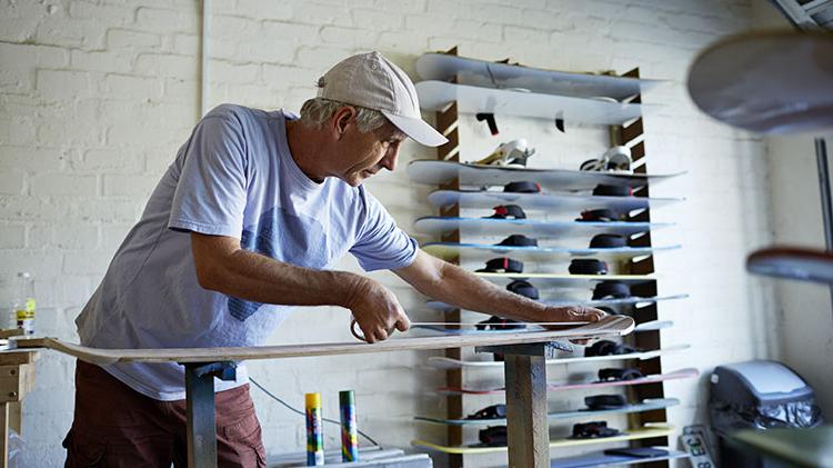 A man is working on a ski board in his shop.